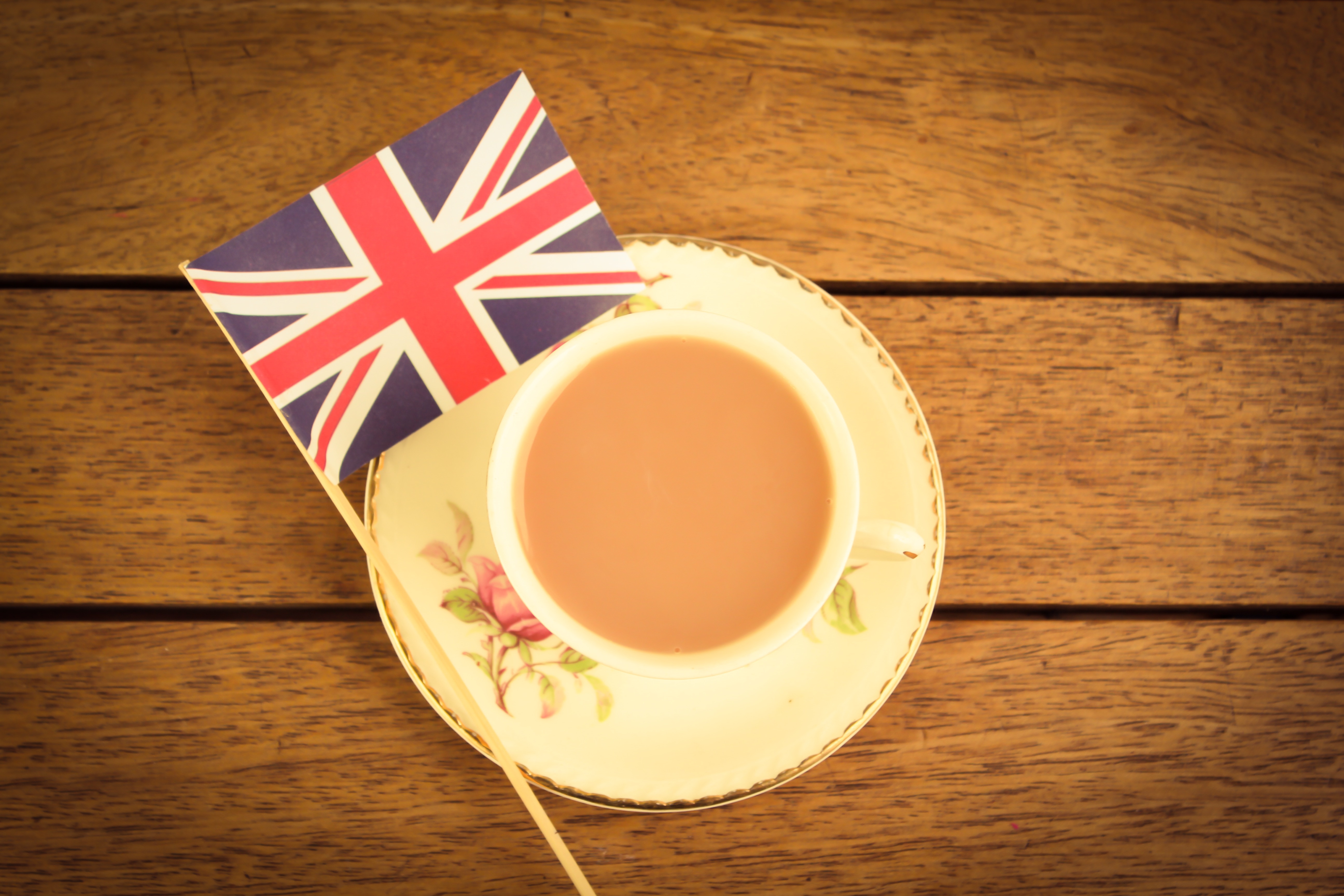 A cup of tea and a union jack on a wooden table